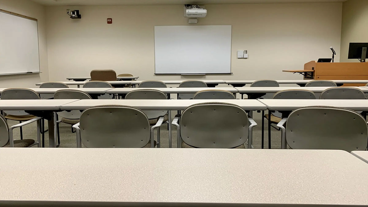 Classroom Saratoga 01‑330 with rows of tables and chairs facing a whiteboard, projection screen, and instructor podium.