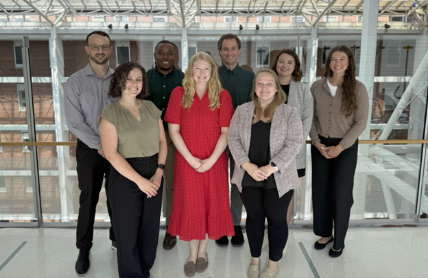 Group of eight preceptors, standing, with five individuals in the back row, three individuals in the front row, smiling